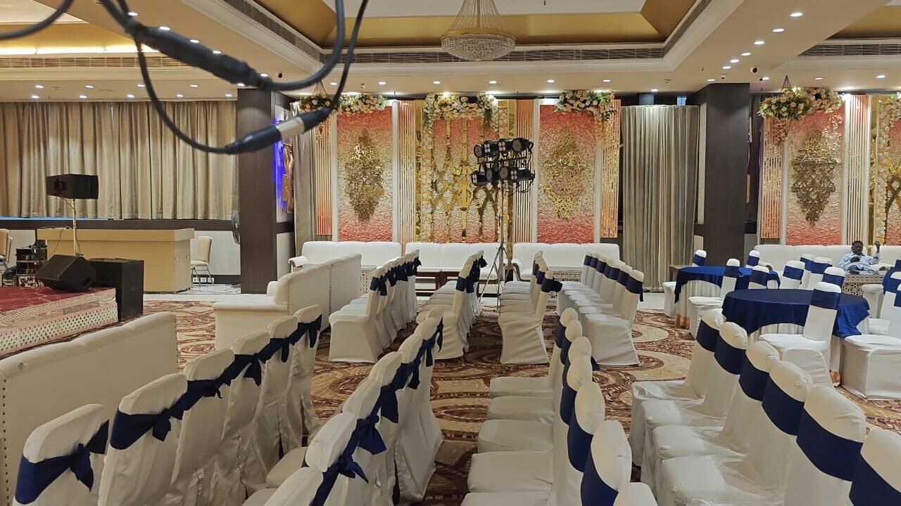 Decorated gala stage with floral panels and rows of blue-sashed seating