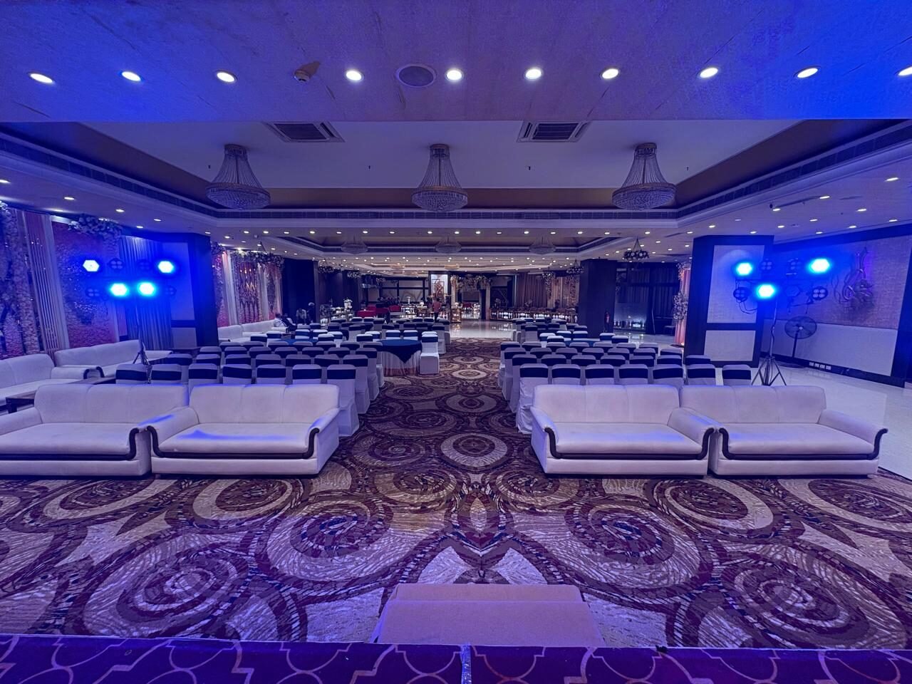 Blue-lit lounge seating facing the stage in the gala hall